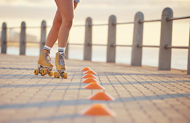 Image showing Woman roller skating with fitness cones outdoor on the promenade at the beach during summer. Girl practicing her skating skill while training for a sports activity in nature at the ocean.