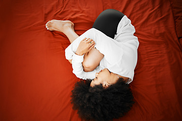 Image showing Pain, stomach ache and period with a young woman holding her tummy and curled up while suffering from menstruation symptoms. Sore, hurt or illness with a sick female lying on a bed in her home