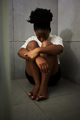 Image showing Sad, unhappy and depressed student sitting alone on the floor of a bathroom in school. Lonely, upset and depressed teen girl struggling with bullying and mental health in the corridor