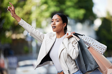 Image showing Retail, shopping and taxi with black woman showing hand sign for transport in an urban city. Female shopper looking fashionable with bags of discount sale purchase, waiting for a cab downtown