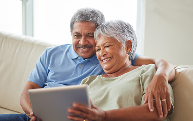 Image showing Senior couple, tablet and communication on social media or video call with elderly husband and wife relaxing on the couch at home. Man and woman reading retirement savings insurance on a banking app