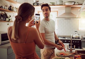 Image showing Cooking man sticking out tongue to make silly, goofy and funny face to pose for a photo while making food in the kitchen at home. Crazy, fun and happy couple enjoying a playful moment while bonding