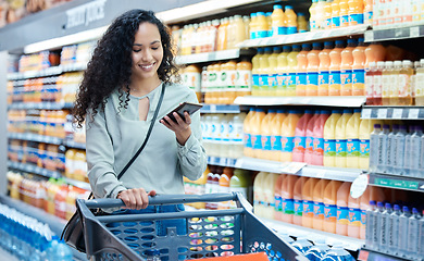 Image showing Grocery shopping, phone and woman using technology in a food store with groceries at a shop. Retail customer multitask in a supermarket walking with a mobile in a juice stock aisle and a happy smile