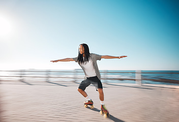 Image showing Man roller skating on the promenade at the beach during a summer holiday for fun and exercise. Young, fit and healthy guy skating for a fitness workout on boardwalk in nature by the ocean on vacation