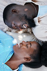 Image showing Love, happiness and black couple laying outdoors on the floor with blankets to relax in a park. Happy, care and African man and woman with a smile resting while on a date in nature by a garden.