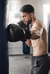 Image showing Punching bag, boxing and boxer man in workout training or exercise in a gym. Strong, powerful and serious athlete or personal trainer with fitness gear for muscle strength, wellness or health goals