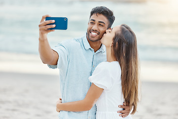 Image showing Travel, vacation and selfie by couple kiss on a beach holiday, bonding and having fun on seaside getaway. Young man and woman embrace, enjoying their relationship and romance on a romantic trip