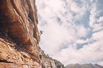 Image showing Rock, sport and mountain adventure man climber free climbing rocks in the mountains. Sports person in nature on a outdoor cliff wall experience a freedom lifestyle and healthy strength challenge