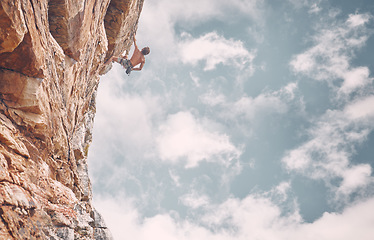 Image showing Rock climbing, sports and adventure with man on mountain against a blue sky background for fitness, challenge and training. Motivation, freedom and strong male athlete on cliff for adrenaline