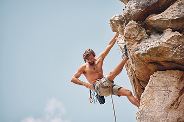 Image showing Mountain or rock climbing, cliff hanging and adrenaline junkie out on adventure and checking his safety equipment, hook and rope. Fearless man doing fitness, exercise and workout during extreme sport