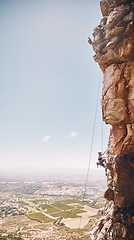 Image showing Person rock climbing on a mountain cliff for a challenge in nature with a blue sky and copy space. Woman climber on a rock wall for a fitness workout, exercise and sports training outdoors.