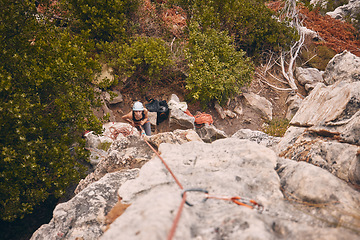 Image showing Climbing, abseiling and adventure with a woman climber hiking on a mountain outside in nature, the woods or the forest. Sports, health and fitness with a female holding a rope and scaling a rock