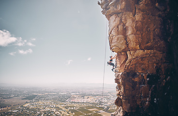 Image showing Mountain, rock climbing and sport with a sports woman and climber abseiling on a mountainside outdoor in nature. Fitness, exercise and training with a female athele using a rop to climb a cliff