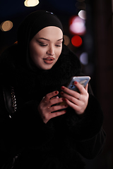 Image showing uropean Muslim Hijabi Business Lady checking her phone on urban city street at night