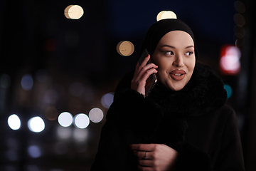 Image showing uropean Muslim Hijabi Business Lady checking her phone on urban city street at night