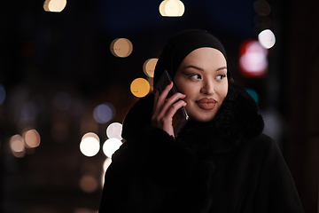 Image showing uropean Muslim Hijabi Business Lady checking her phone on urban city street at night