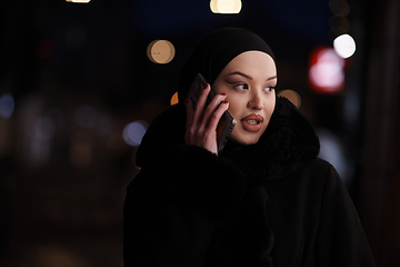 Image showing uropean Muslim Hijabi Business Lady checking her phone on urban city street at night