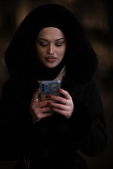 Image showing Muslim woman walking on urban city street on a cold winter night wearing hijab