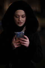 Image showing Muslim woman walking on urban city street on a cold winter night wearing hijab