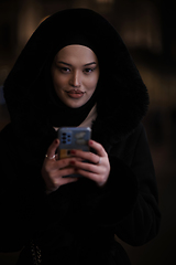 Image showing Muslim woman walking on urban city street on a cold winter night wearing hijab