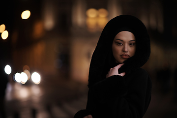 Image showing Muslim woman walking on urban city street on a cold winter night wearing hijab