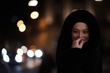 Image showing Muslim woman walking on urban city street on a cold winter night wearing hijab