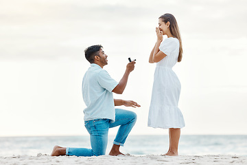 Image showing Engagement, beach and a couple with a marriage proposal with a ring while on romantic vacation. Love, romance and happy couple getting engaged while on a summer holiday in nature by the ocean.