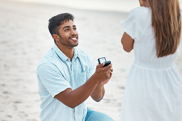 Image showing Proposal, surprise and engagement with wedding ring on beach with indian man on knee for love, commitment and marriage. Save the date, gift and diamond jewellery present for woman for romance