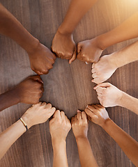 Image showing Hands, collaboration and motivation with the fists of a team in a circle or huddle on a wooden background from above. Teamwork, goal and target with a group of people ready for success in unity