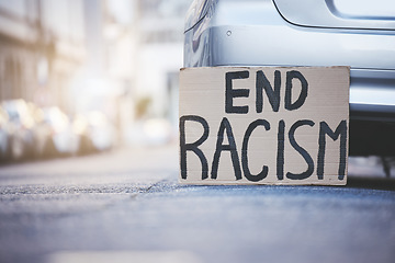 Image showing End racism sign cardboard poster in urban street background for solidarity, human rights and race problem. Advertising of protest board for freedom, equality and stop violence with mockup lens flare