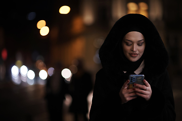 Image showing Muslim woman walking on urban city street on a cold winter night