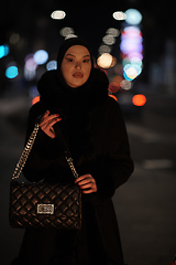 Image showing Muslim woman walking on urban city street on a cold winter night wearing hijab