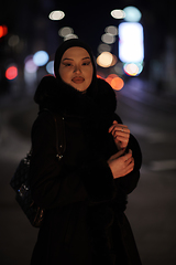 Image showing Muslim woman walking on urban city street on a cold winter night wearing hijab