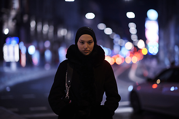 Image showing Muslim woman walking on an urban city street on a cold winter night wearing hijab