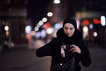 Image showing Muslim woman walking on urban city street on a cold winter night wearing hijab