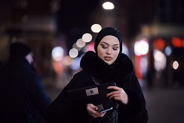 Image showing Muslim woman walking on urban city street on a cold winter night wearing hijab