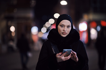 Image showing Muslim woman walking on urban city street on a cold winter night wearing hijab