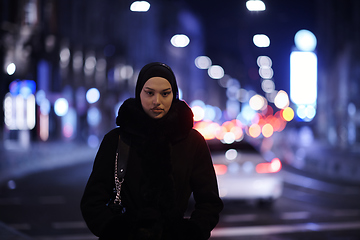 Image showing Muslim woman walking on an urban city street on a cold winter night wearing hijab