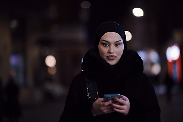 Image showing Muslim woman walking on urban city street on a cold winter night wearing hijab