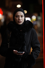 Image showing Muslim woman walking on urban city street on a cold winter night wearing hijab