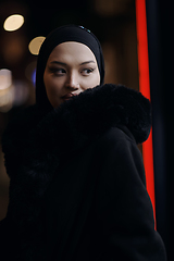 Image showing Muslim woman walking on urban city street on a cold winter night wearing hijab