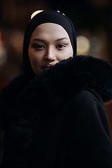 Image showing Muslim woman walking on urban city street on a cold winter night wearing hijab