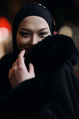 Image showing Muslim woman walking on urban city street on a cold winter night wearing hijab