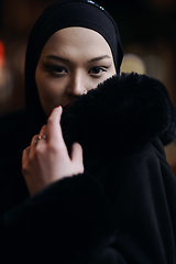 Image showing Muslim woman walking on urban city street on a cold winter night wearing hijab