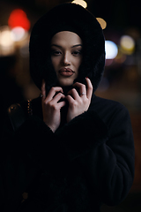 Image showing Muslim woman walking on urban city street on a cold winter night wearing hijab