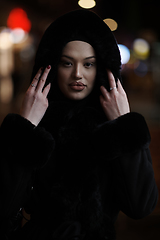 Image showing Muslim woman walking on an urban city street on a cold winter night wearing hijab