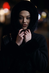 Image showing Muslim woman walking on urban city street on a cold winter night wearing hijab