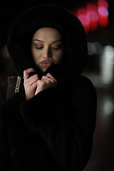 Image showing Muslim woman walking on urban city street on a cold winter night wearing hijab