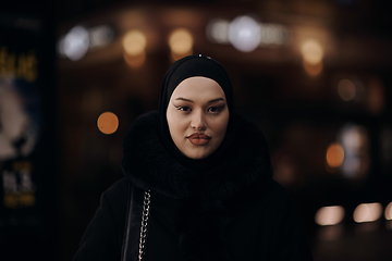 Image showing Muslim woman walking on urban city street on a cold winter night wearing hijab