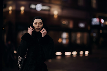 Image showing Muslim woman walking on urban city street on a cold winter night wearing hijab